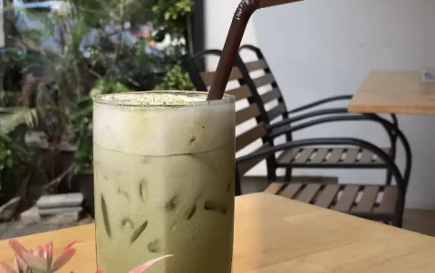 Iced Matcha Tea with a straw, on a table in the sunshine. Just one of the healthy options in Rawai at Poached Rawai Beach, Phuket, Thailand.