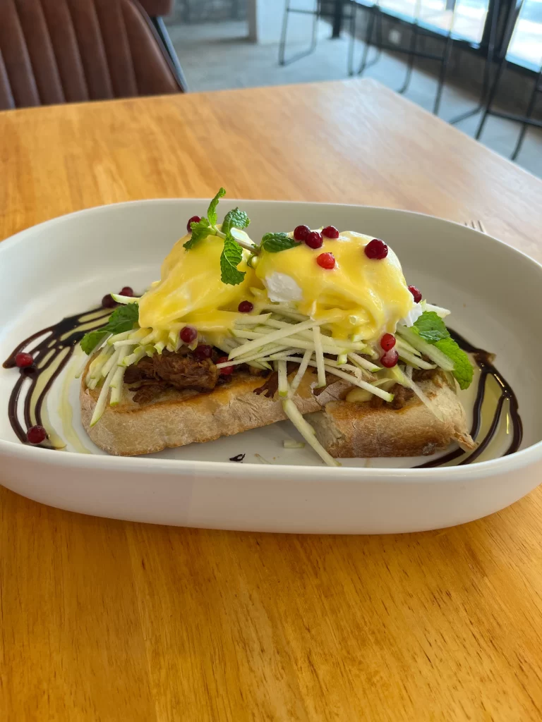 Pulled pork eggs benedict on sourdough bread topped with apple slaw, 2 poached eggs, creamy hollandaise sauce and mint leaves. Great food in Rawai at Poached Breakfast Cafe Rawai, Phuket, Thailand