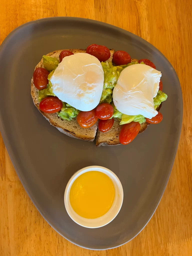 Smashed avocado, roasted tomato and poached eggs on sourdough bread at Poached Breakfast Cafe Rawai, Phuket, Thailand. A good wifi coffee shop in Rawai.