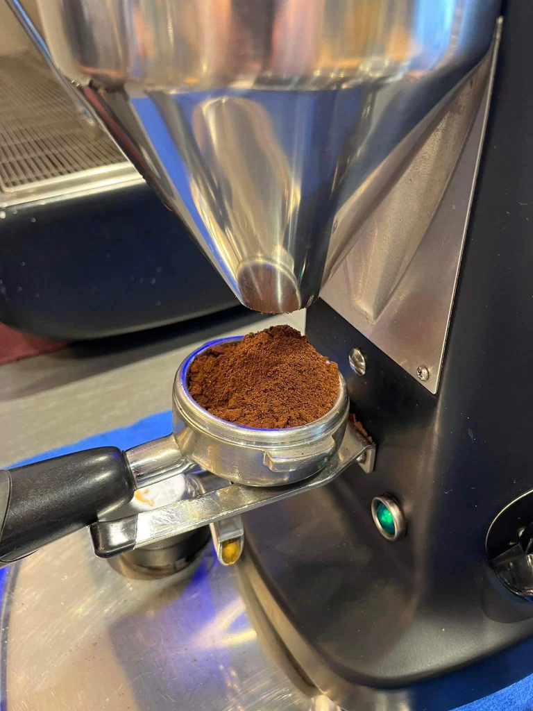 Ground coffee beans in a machine at the best coffeehouse in Rawai: Poached Breakfast Cafe Rawai, Phuket, Thailand