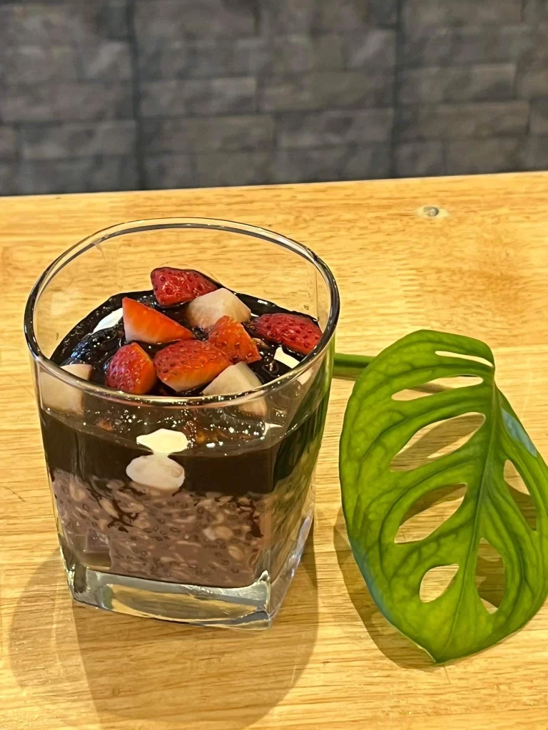 Overnight oats with strawberries and chocolate next to a leaf at Poached Breakfast Cafe Rawai, Phuket, Thailand - the answer to the question 'where to eat in rawai?'