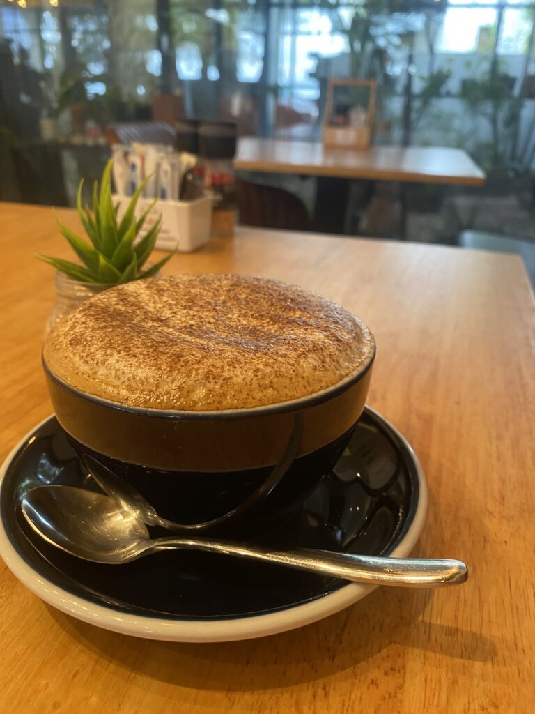 Cappuccino with a fluffy foam next to a succulent plant at one of the best restaurants that deliver in Rawai: Poached Breakfast Cafe, Rawai,, Phuket, Thailand