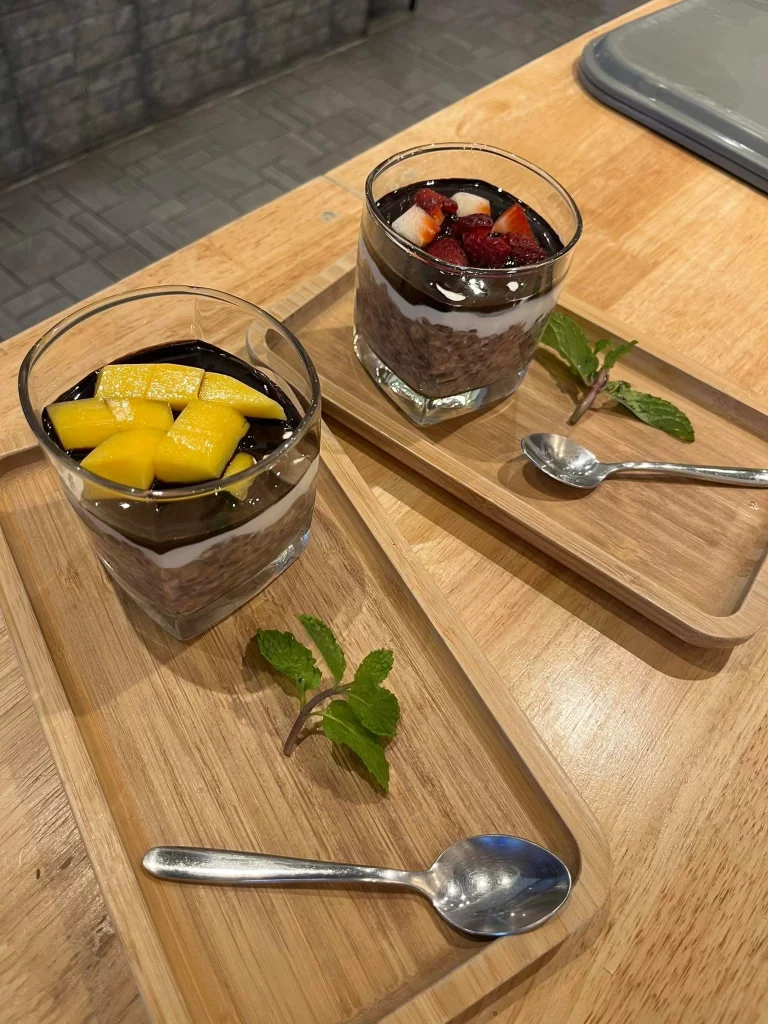 Two orders of delicious chocolate topped overnight oats with mango and strawberries at In the foreground you can see eggs benedict and in the background you can see banana bread at the best healthy restaurant in Rawai, Poached Breakfast Cafe, Rawai, Phuket, Thailand