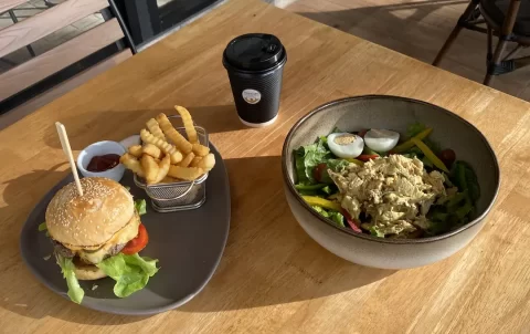 Burger and salad outside on the table at the spot that answers the question, 'What to eat in Nai Harn?' Poached Breakfast Cafe Rawai, Phuket, Thailand