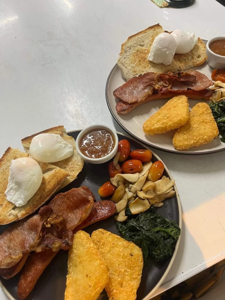 2 plates packed with a fry up style breakfast with hash browns, poached eggs, sourdough bread, mushrooms, tomatoes, and bacon at the spot with the best cafe menu in Rawai: Poached Breakfast Cafe, Rawai, Phuket, Thailand