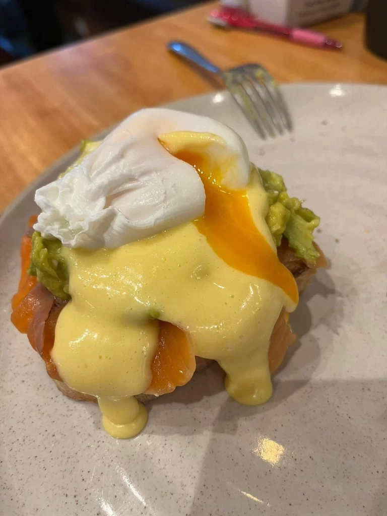 Smoked Salmon Eggs Benedict with smashed avocado on a plate with oozy runny poached eggs at a super duper cafe in Rawai: Poached Breakfast Cafe Rawai, Phuket, Thailand