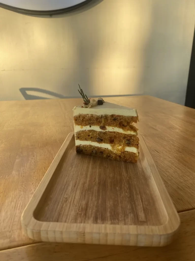 Carrot cake with cream cheese frosting on a table. This makes for the perfect sweet treat before you head off to a beach club in Rawai. Only at Poached Breakfast Cafe Rawai, Phuket, Thailand.