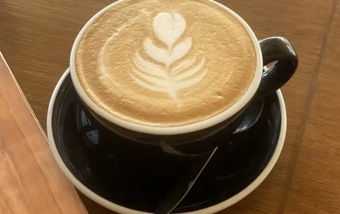 A latte in a large cup with a leaf made with foam in the top. We serve the best specialty coffee in Rawai at Poached Breakfast Cafe, Rawai, Phuket, Thailand