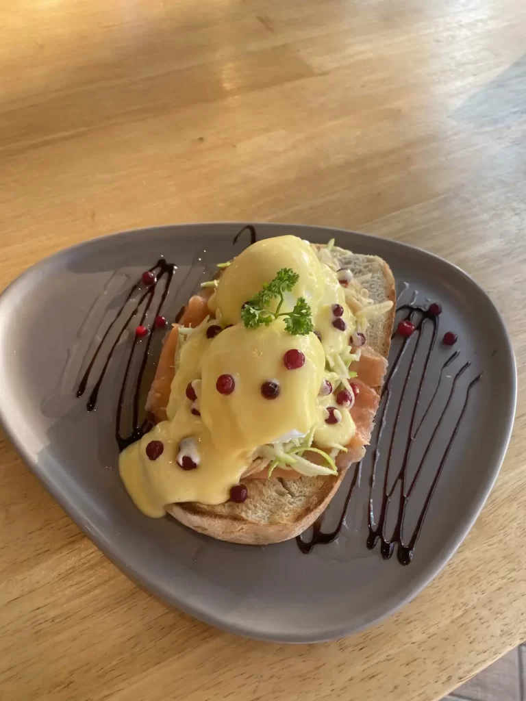 Smoked salmon eggs benedict on a triangle plate outdoors at the cafe with the best tea in Rawai: Poached Breakfast Cafe Rawai, Phuket, Thailand