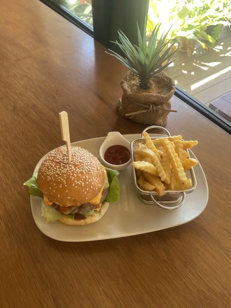 Spicy beef burger on a plate with fries and ketchup. We serve the best specialty coffee in Rawai at Poached Breakfast Cafe, Rawai, Phuket, Thailand