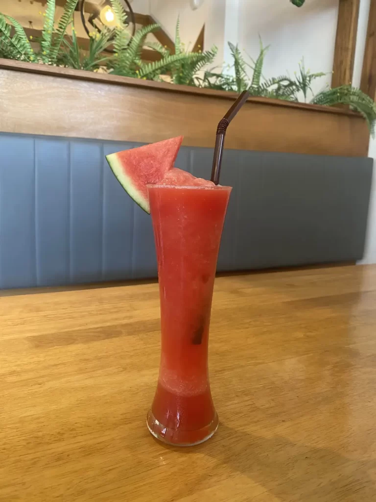 Watermelon smoothie on a table next to our booth seats. The best dessert in Rawai at Poached Breakfast Cafe Rawai, Phuket, Thailand