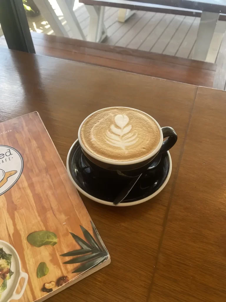 Latte with menu at the spot with the best ground coffee near Nai Harn at Poached Breakfast Cafe Rawai, Phuket, Thailand