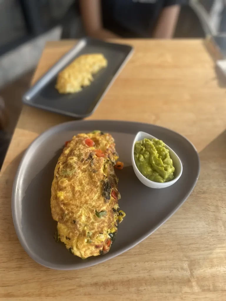 Omelette on the table with smashed avocado at the spot with the best omelette near Nai Harn, Poached Breakfast Cafe Rawai, Phuket, Thailand
