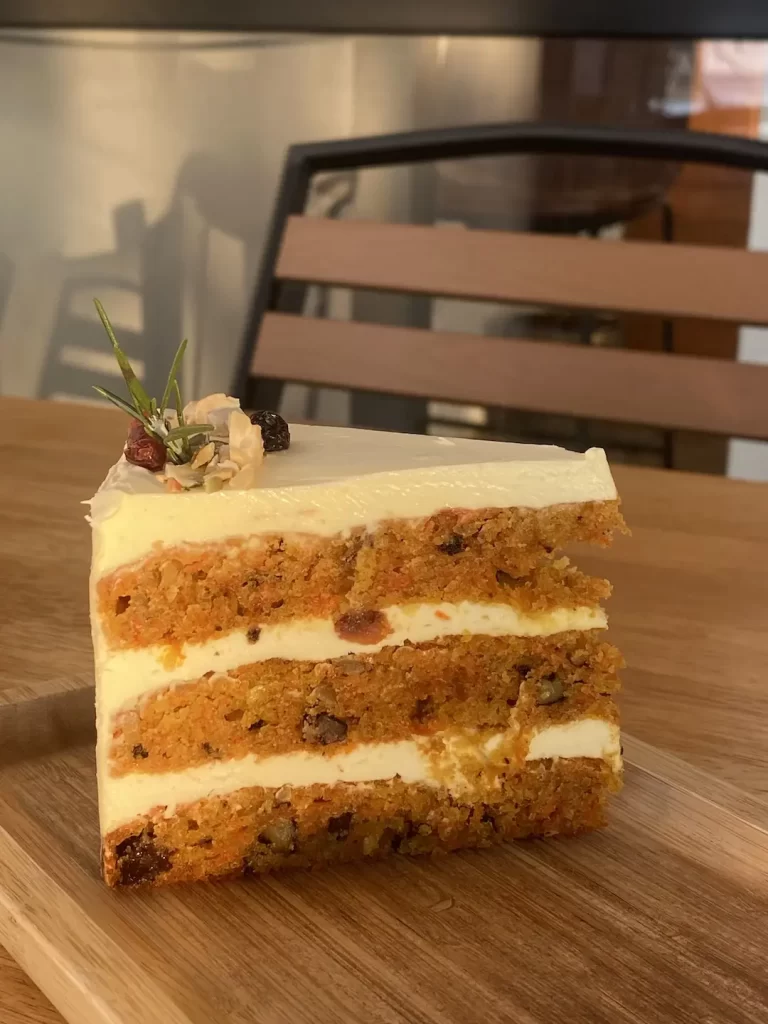 Spiced carrot cake topped with dried fruit and rosemary as well as a cream cheese frosting at the spot with the best apple pie near Nai Harn: Poached Breakfast Cafe Rawai, Phuket, Thailand