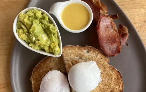 Healthy breakfast with smashed avocado, 2 poached eggs, sourdough bread, hollandaise sauce and lean bacon at the spot to eat at before visiting the best viewpoints in Nai Harn: Poached Breakfast Cafe Rawai, Phuket, Thailand