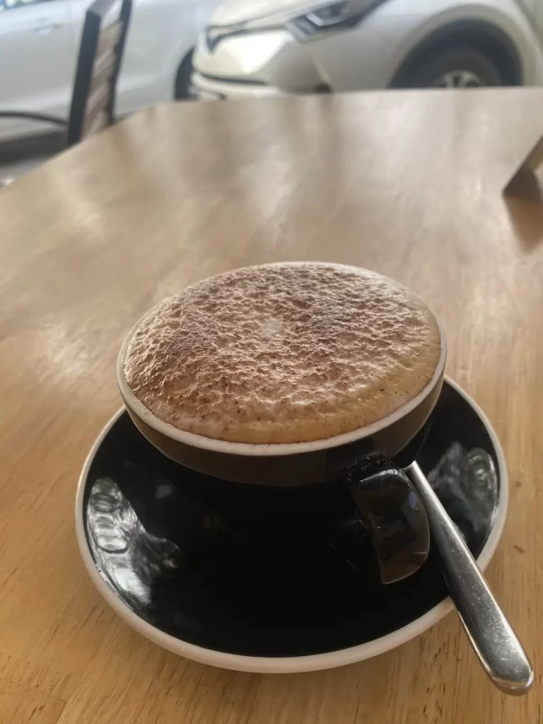 Frothy cappuccino on a table at the top local cafe near Nai Harn: Poached Breakfast Cafe Rawai, Phuket, Thailand