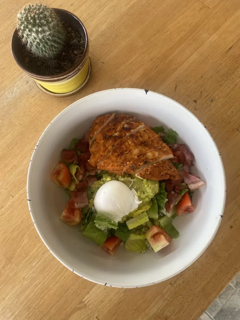 Chicken Cobb salad with avocado, egg and bacon next to a cactus at the top local cafe near Nai Harn: Poached Breakfast Cafe Rawai, Phuket, Thailand