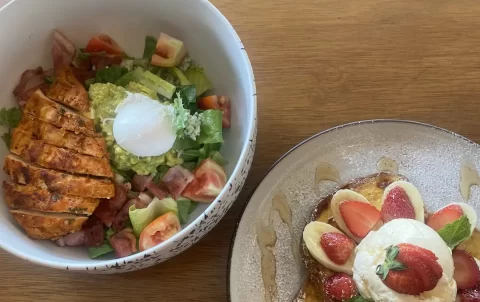 Cobb salad with poached egg next to a plate of french toast topped with banana, strawberries and a scoop of ice cream. Only at the place with the best coffee menu in Nai Harn: Poached Breakfast Cafe, Rawai, Phuket, Thailand