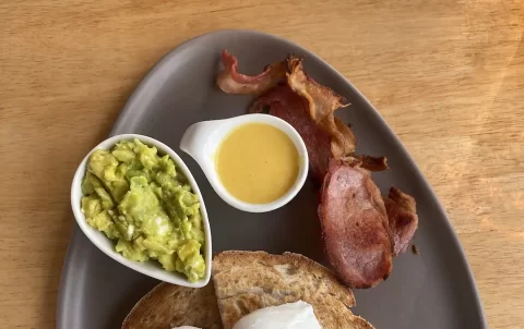 2 poached eggs on sourdough toast with sides of hollandaise sauce, bacon and smashed avocado. A great spot to eat if you're staying at one of the hotels in Rawai. Only at Poached Breakfast Cafe Rawai, Phuket, Thailand