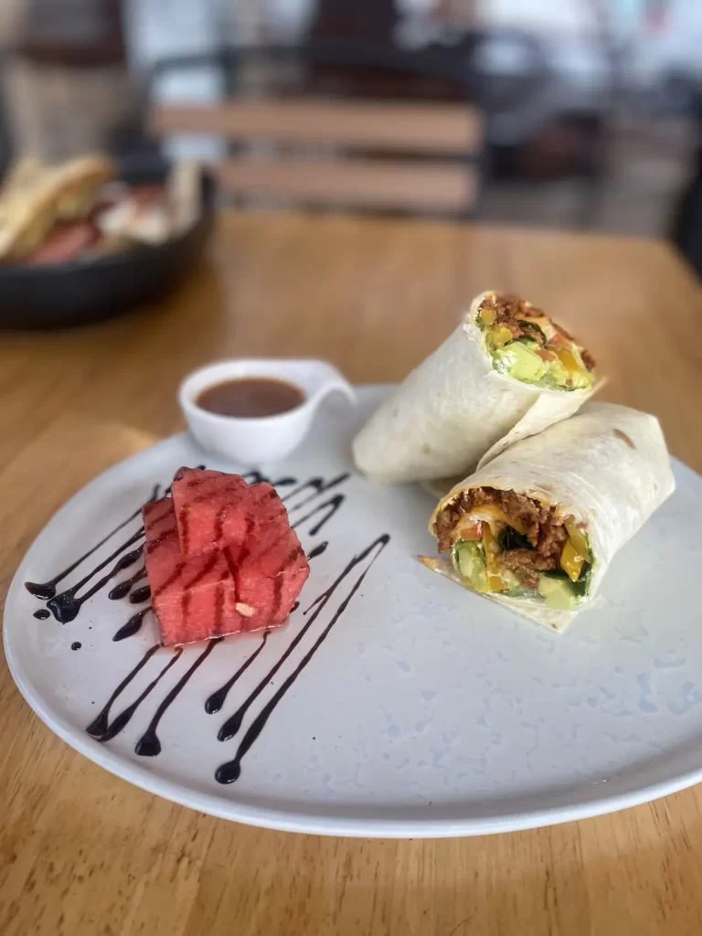 Spicy sausage wrap with avocado and a side of watermelon. Only at the place with the best coffee menu in Nai Harn: Poached Breakfast Cafe, Rawai, Phuket, Thailand