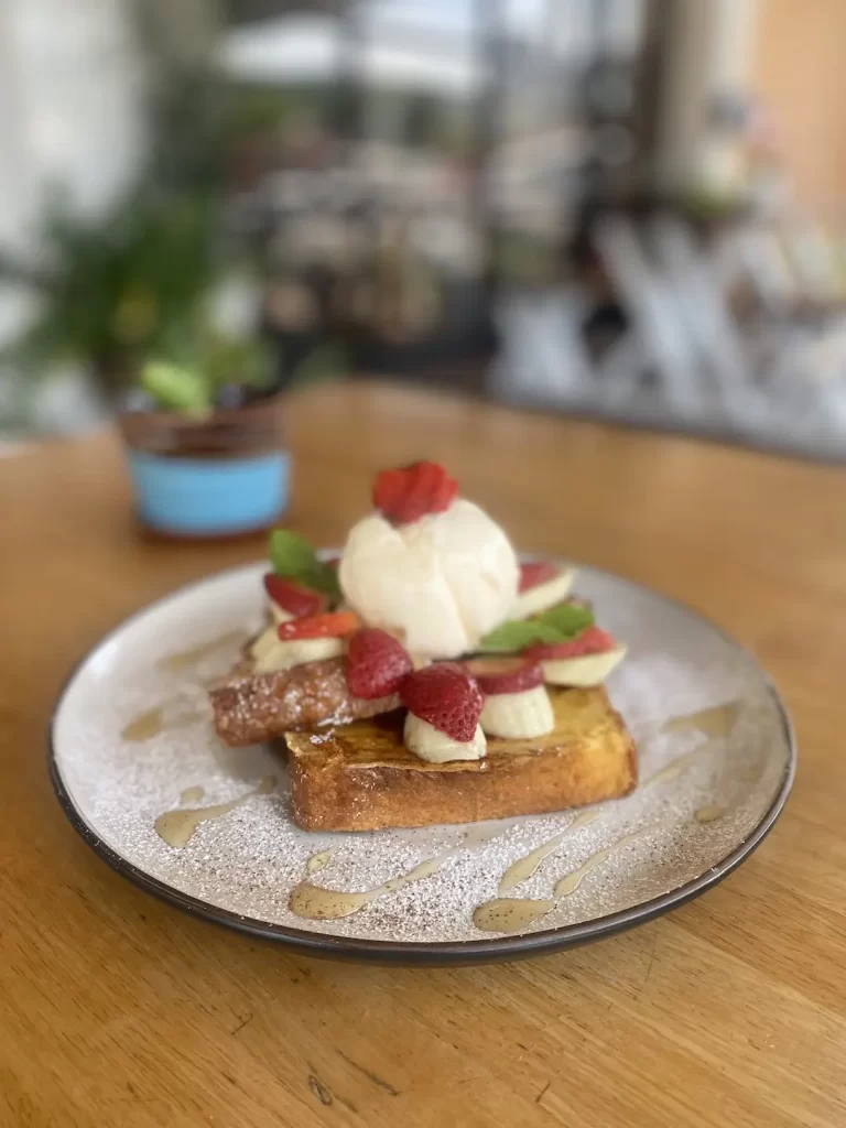 French toast stack with strawberries, banana and an ice cream scoop on a round plate. This is a great place to eat before checking out spots for motorbike hire in Rawai. Only at Poached Breakfast Cafe Rawai, Phuket, Thailand