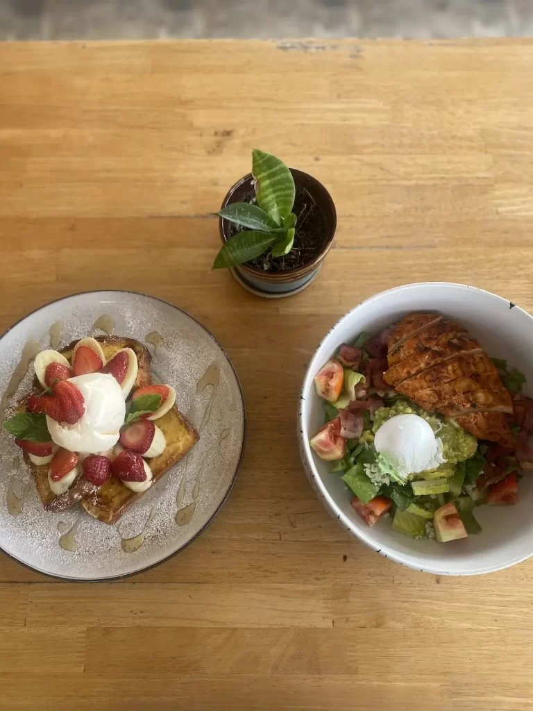 French toast stack with strawberries, banana and an ice cream scoop on the right. A bowl of chicken cobb salad with smashed avocado, poached egg, bacon bits and blue cheese dressing. This is a great place to eat before checking out spots for motorbike hire in Rawai. Only at Poached Breakfast Cafe Rawai, Phuket, Thailand